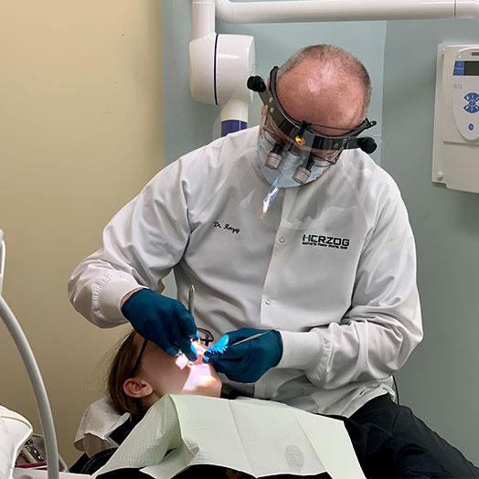 Dr Herzog cleaning a patient's teeth