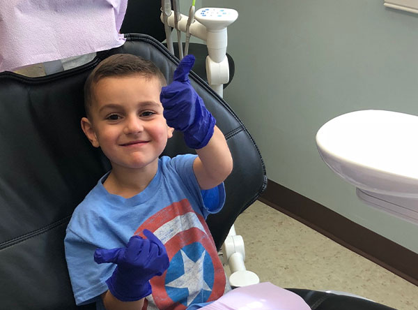 child giving thumbs up in dentist's chair